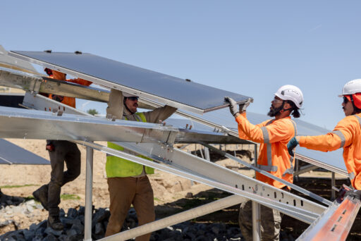 construction workers help each other install panels